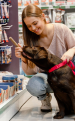 Uma mulher com seu cachorro preto em um pet shop